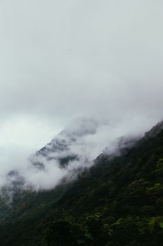 薄雾和云层笼罩着迷人的山峰，展现了大自然的美丽