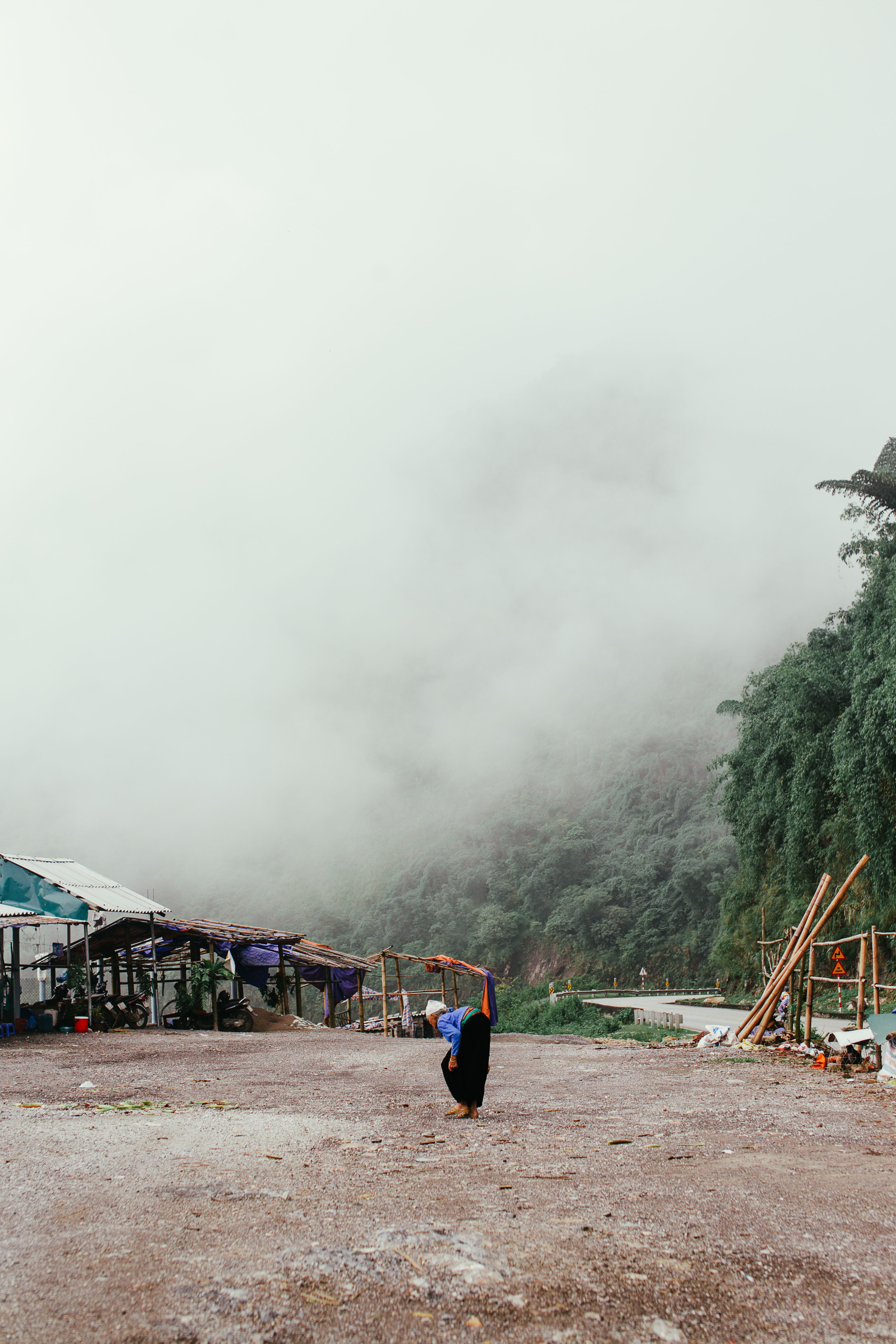 一个女人走过雾气笼罩的山村，营造出宁静而神秘的氛围