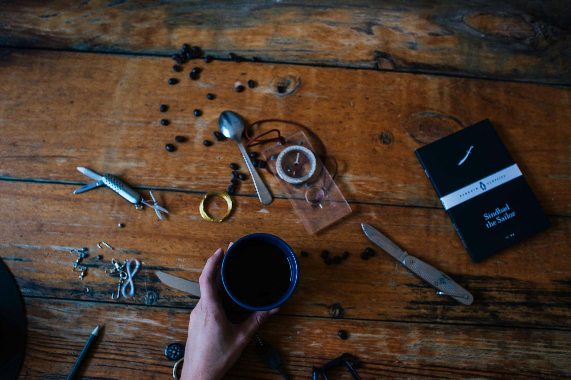 An artistic composition featuring a coffee cup, tools, and a book on a rustic wooden table.