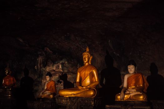 在宁静的洞穴寺庙环境中，金色佛像被昏暗地照亮，凸显了灵性