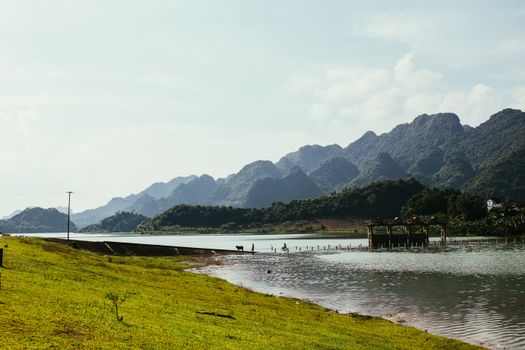 晴朗的天空下，宁静的河流两岸绿草如茵，远处山脉连绵