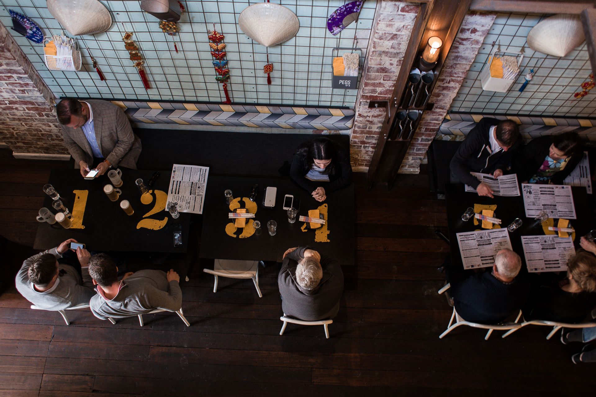 Top-down view of people dining and using phones in a trendy restaurant setting.