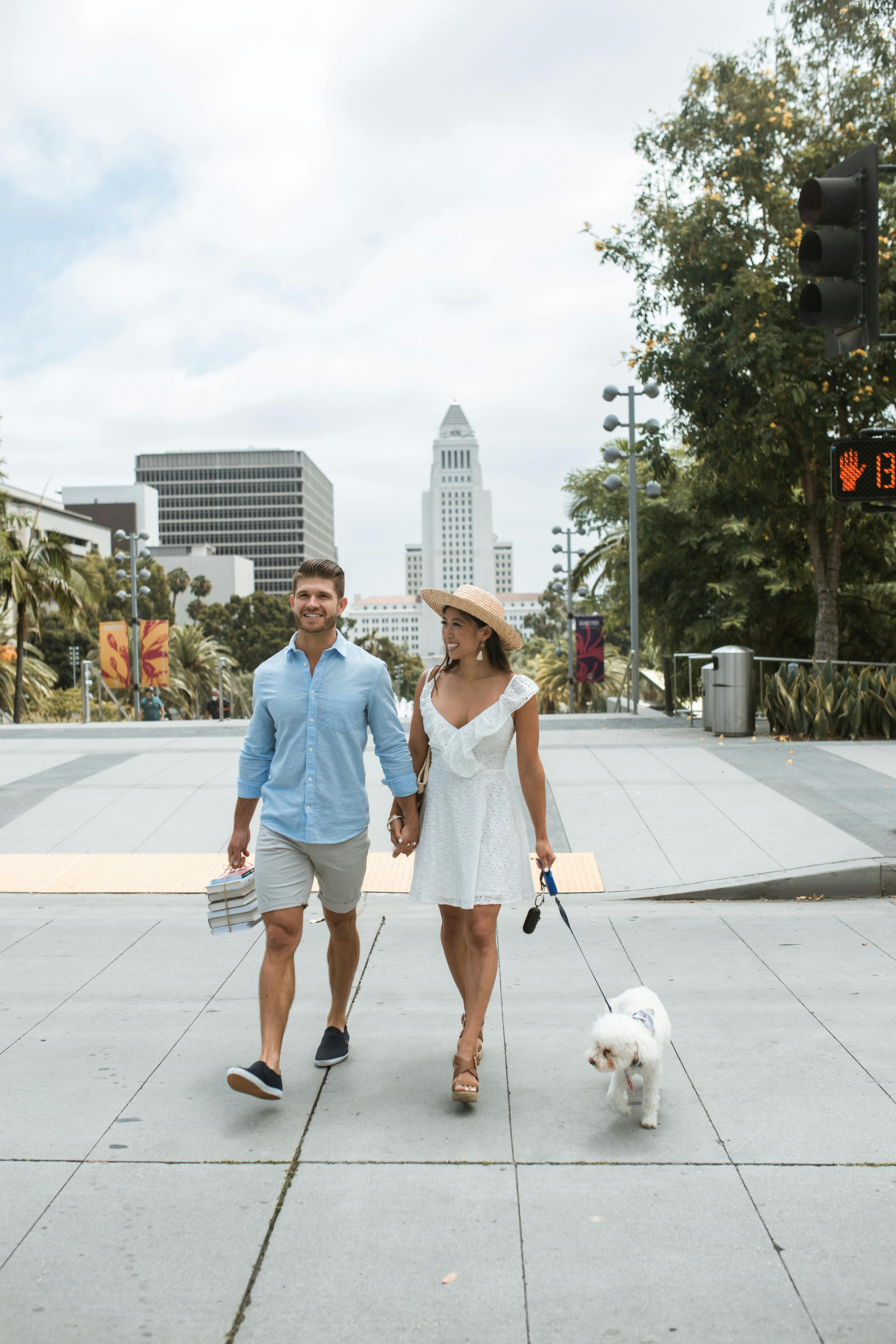 happy couple holding hands while walking the dog in the park