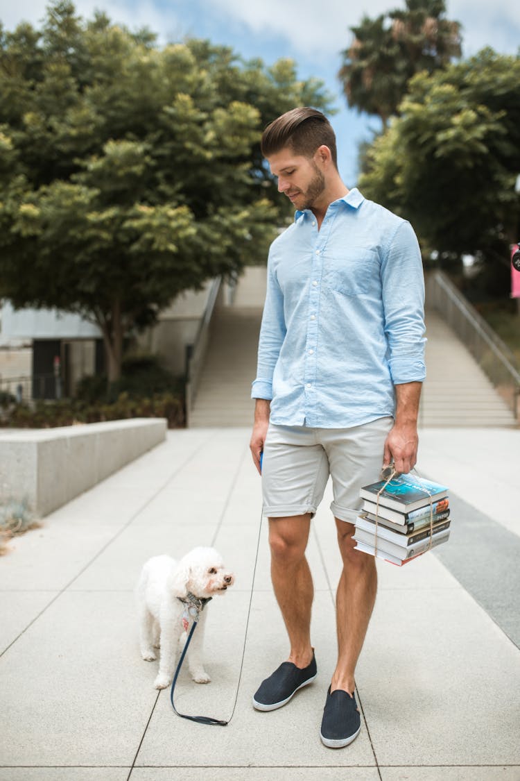 Man Carrying Books With His Dog