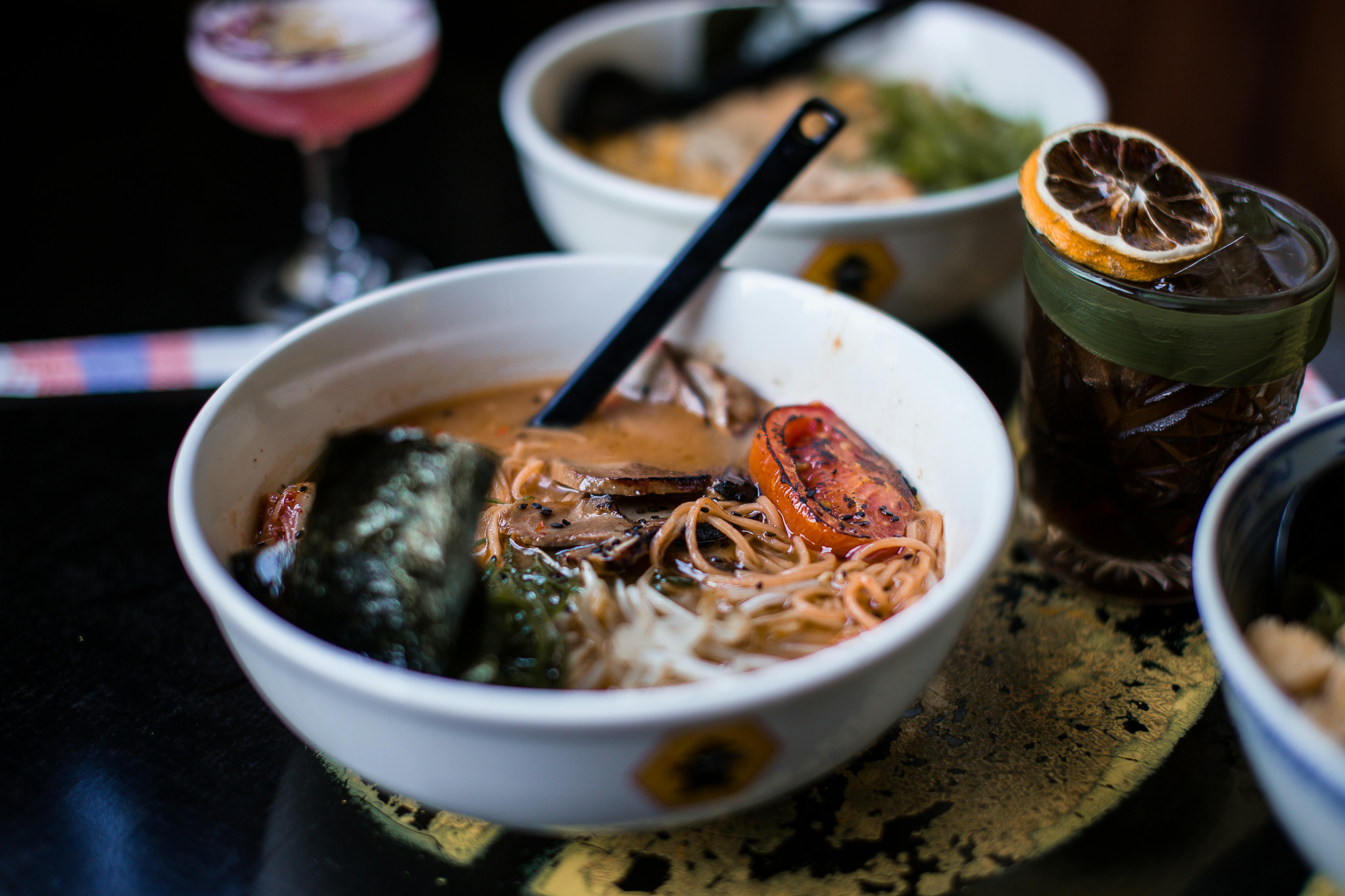 Close-up of a savory ramen bowl featuring noodles, roasted vegetables, and soup in a cozy setting.