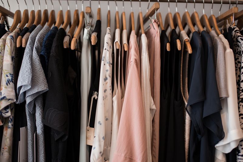 A boutique rail of soft neutral clothing on wooden hangers