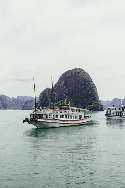 A serene landscape of a cruise boat sailing through Ha Long Bay, known for its limestone islands.