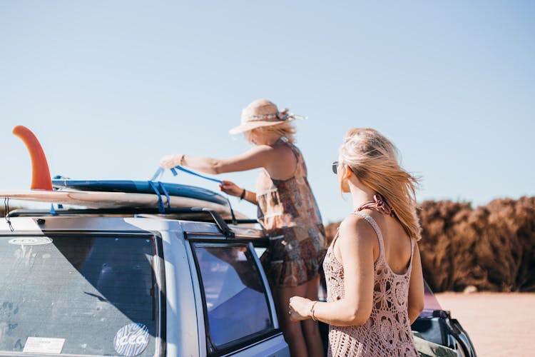 Women Putting Surfboards On A Car Roof