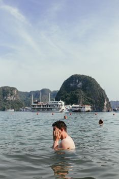 在下龙湾游泳的人，可以看到风景秀丽的石灰岩地层和游轮
