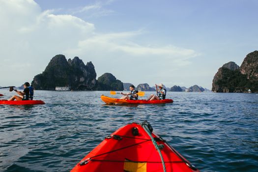 Group kayaking in vibrant ocean setting with stunning rock formations under blue sky.