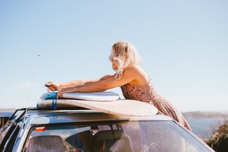 Blonde Person Tying The Surfboards On The Car Roof 