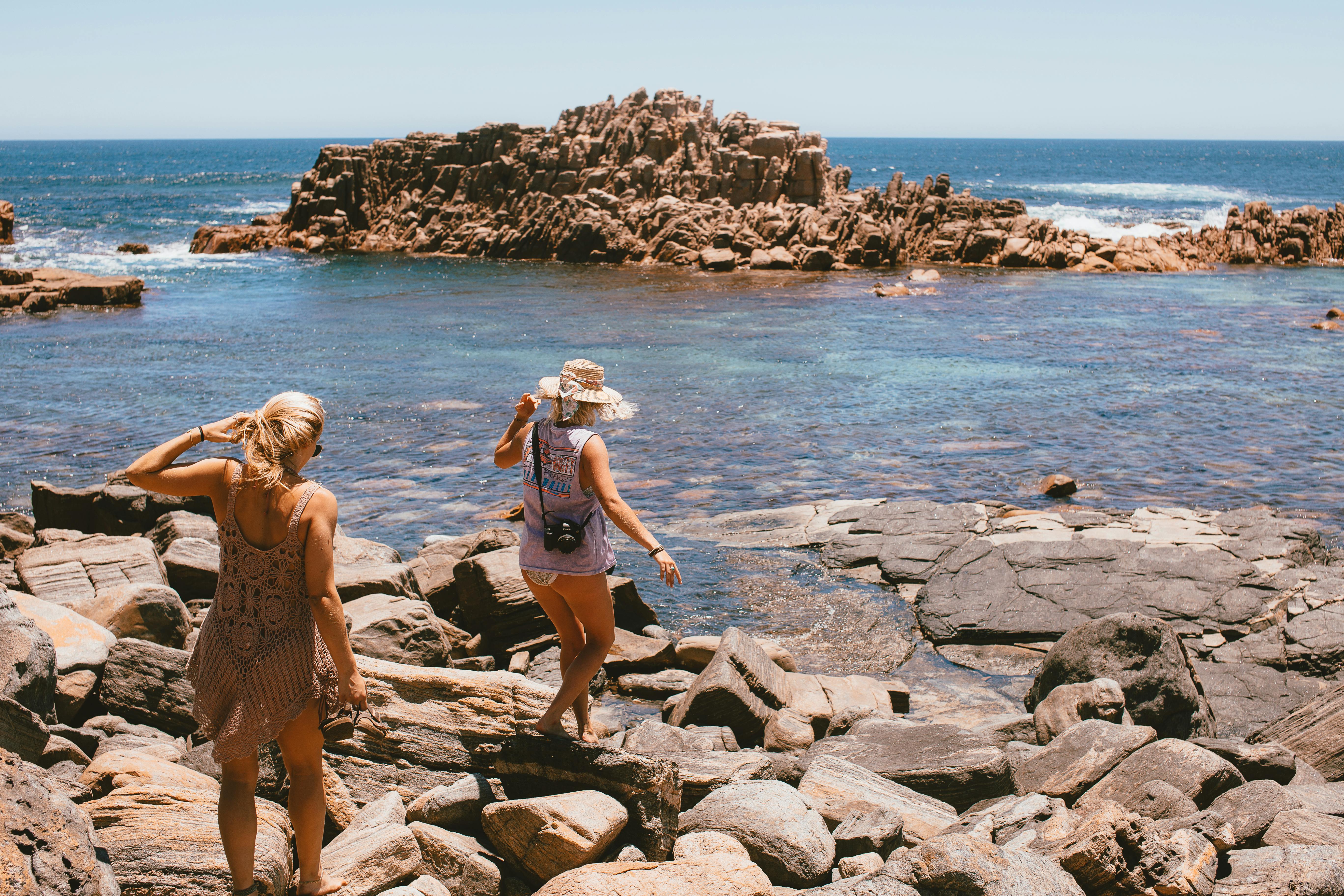 back view of women walking on the rocky shore