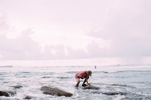 Photo of a Boy Standing in the Water against a Cloudy Sky