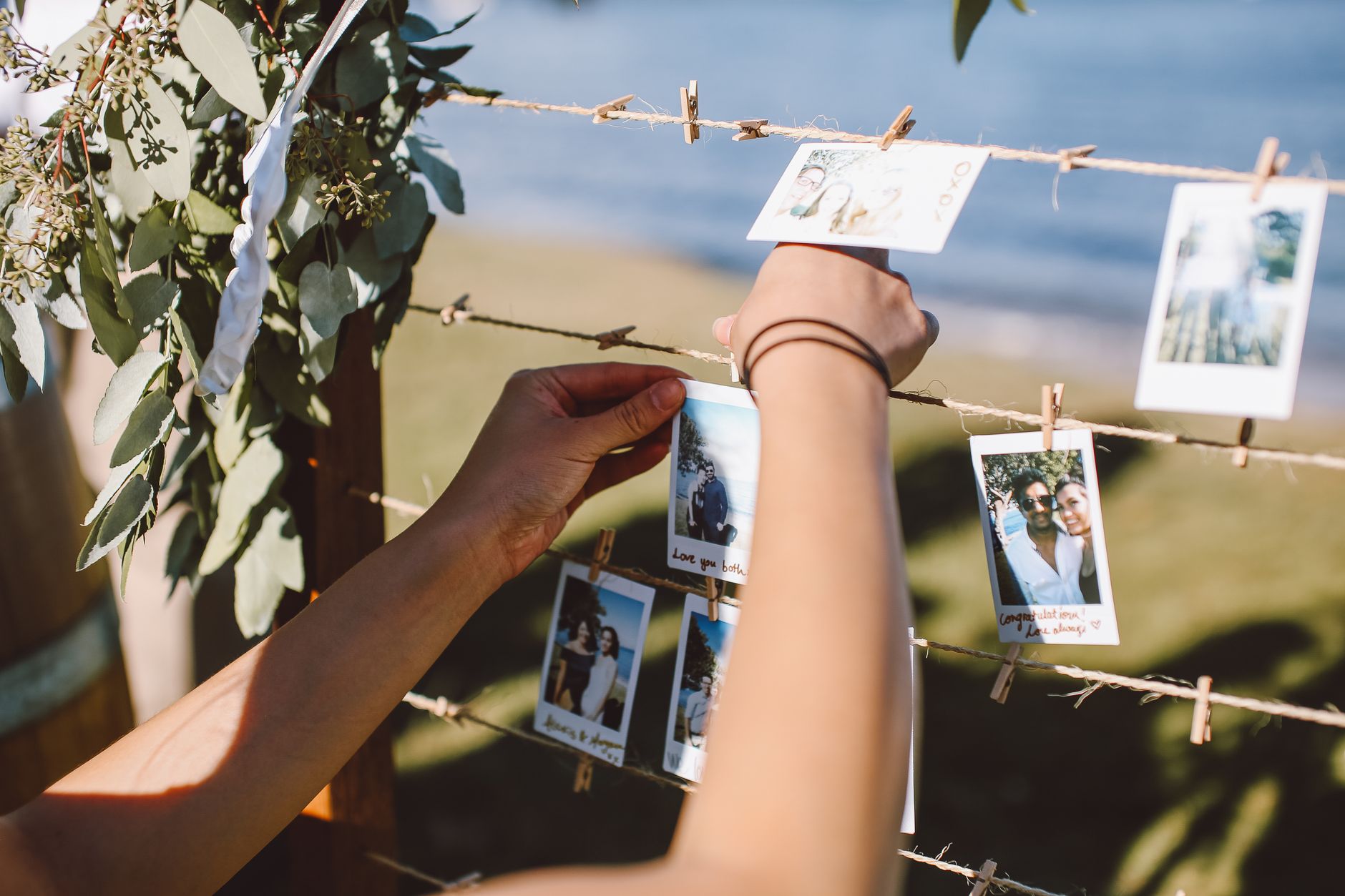 Hands hanging printed photos on a string with wooden clothespins — one of the simplest ways to display wedding guest shots