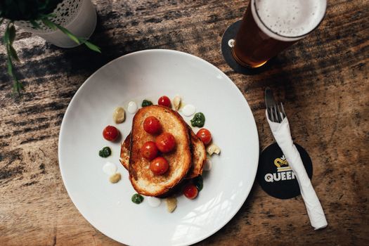 Artistic flatlay of gourmet toast served with cherry tomatoes and sauce on a ceramic plate.