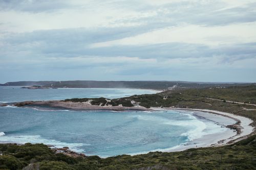 Free A peaceful coastal landscape featuring a calm bay, sandy shores, and lush green vegetation. Stock Photo