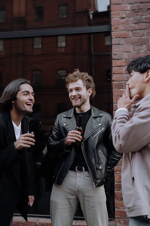 Group of Friends Laughing while Holding Beer Bottles and Smoking Cigarette