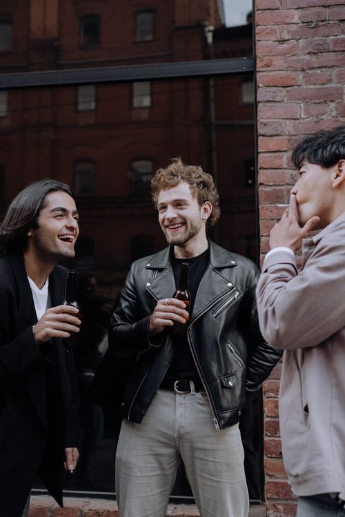 Free Three men enjoying drinks and laughter outdoors, embracing friendship and good times. Stock Photo