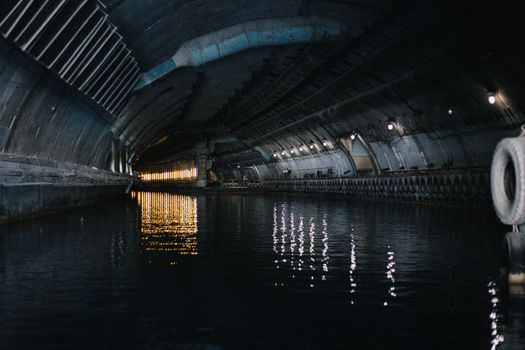 Explore the mysterious atmosphere in this dimly lit underground canal tunnel with captivating reflections on water.