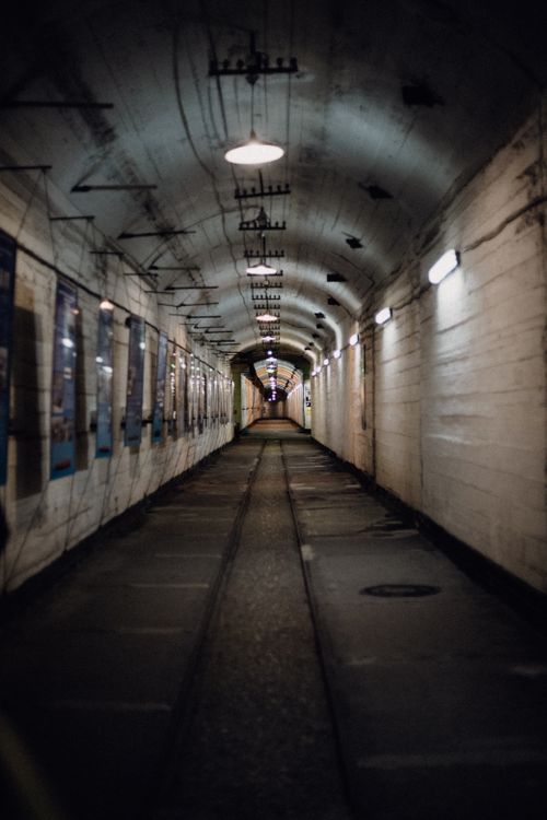 Free A haunting view of an empty, dimly lit underground tunnel with a railroad track. Stock Photo