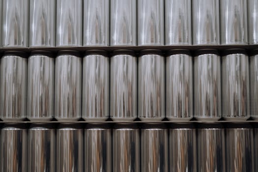 A neatly organized stack of reflective aluminum beverage cans in an industrial setting.