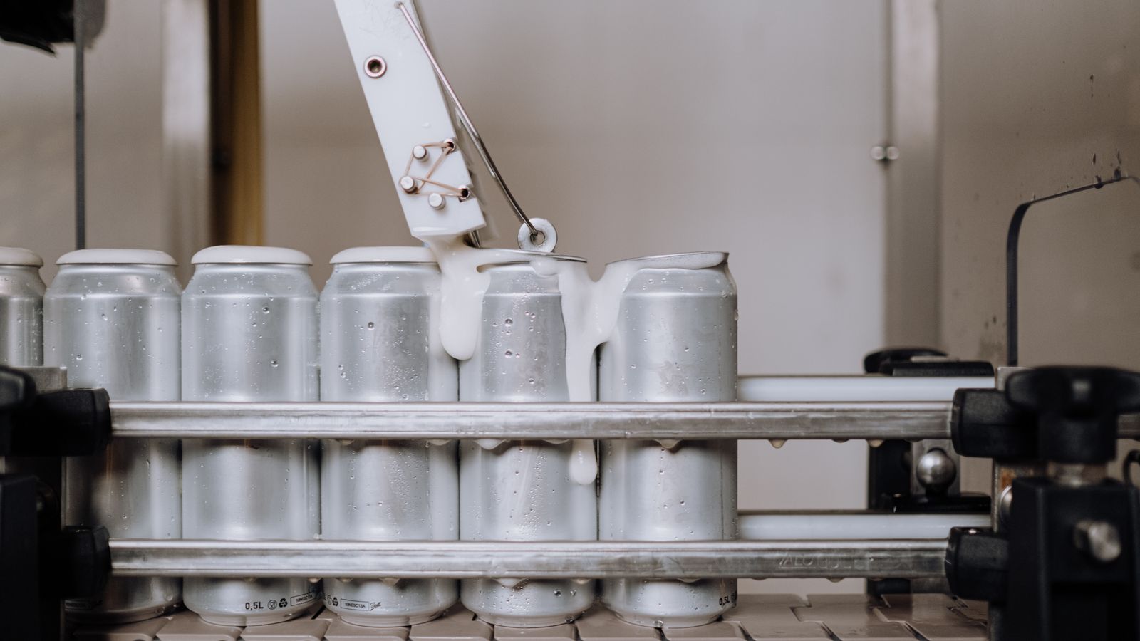Close-up of aluminum cans being filled in an automated brewery assembly line.
