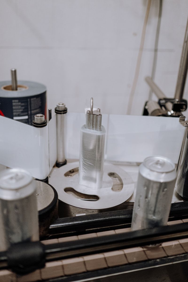 Close-up of an automated system labeling beverage cans in a modern brewery factory