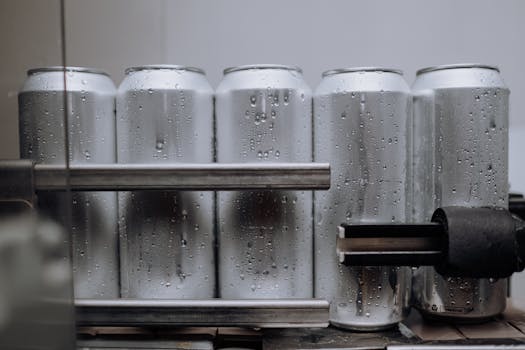 Close-up of condensation-covered aluminum cans on a production line, highlighting cool refreshment.