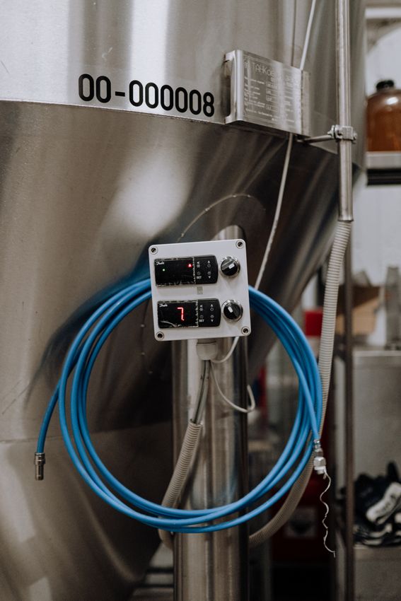 Blue industrial hose connected near a stainless manufacturing tank