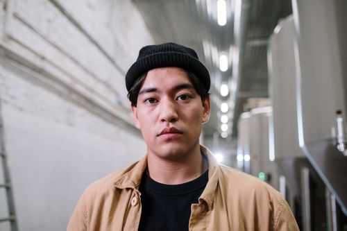 Free A focused portrait of a man wearing a beanie hat in an industrial environment. Stock Photo