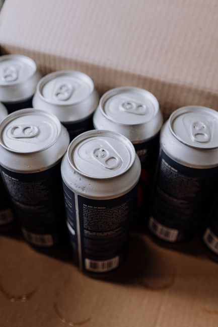 Close-up view of several unopened beverage cans with condensation in a cardboard box.