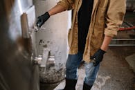 在工业啤酒厂环境中，戴着手套的酿酒师操作着啤酒水龙头