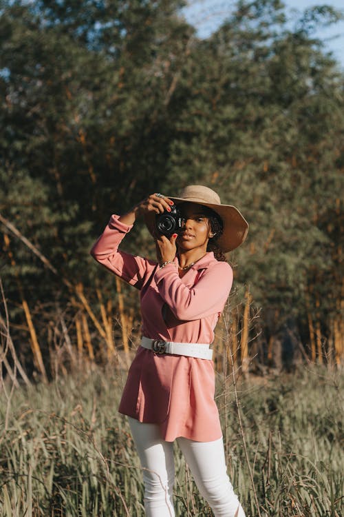 Woman Holding a Camera Standing on the Grass