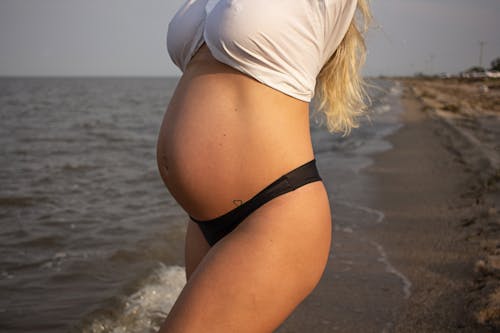 Free Pregnant Woman Standing on Seashore Stock Photo