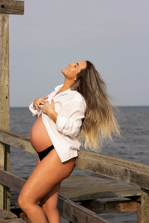 Free Pregnant Woman Leaning on Wooden Railing Stock Photo
