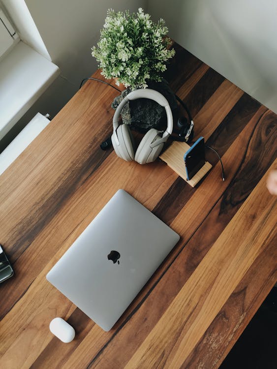 From above of modern laptop and devices placed on wooden table near window at daytime