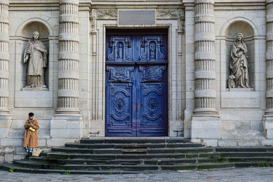 Une femme solitaire se tient devant les portes ornées de bleu de l'église Saint-Étienne du Mont, Paris.