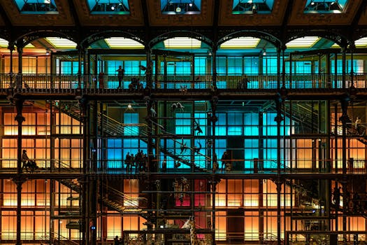 Vibrant multicolored interior view of a Paris museum with silhouetted people and metal structures.