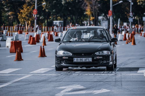 People driving automobile on road with traffic cones