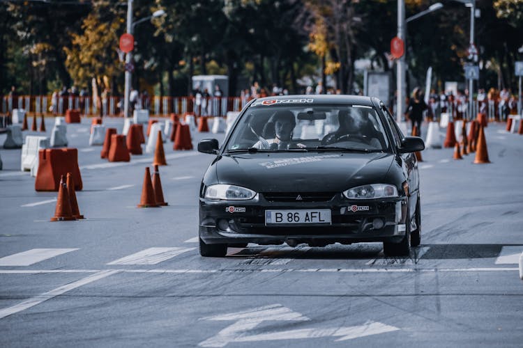 People Driving Automobile On Road With Traffic Cones