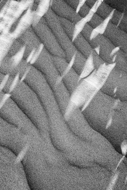 High-contrast black and white photo capturing abstract patterns in sand dunes.