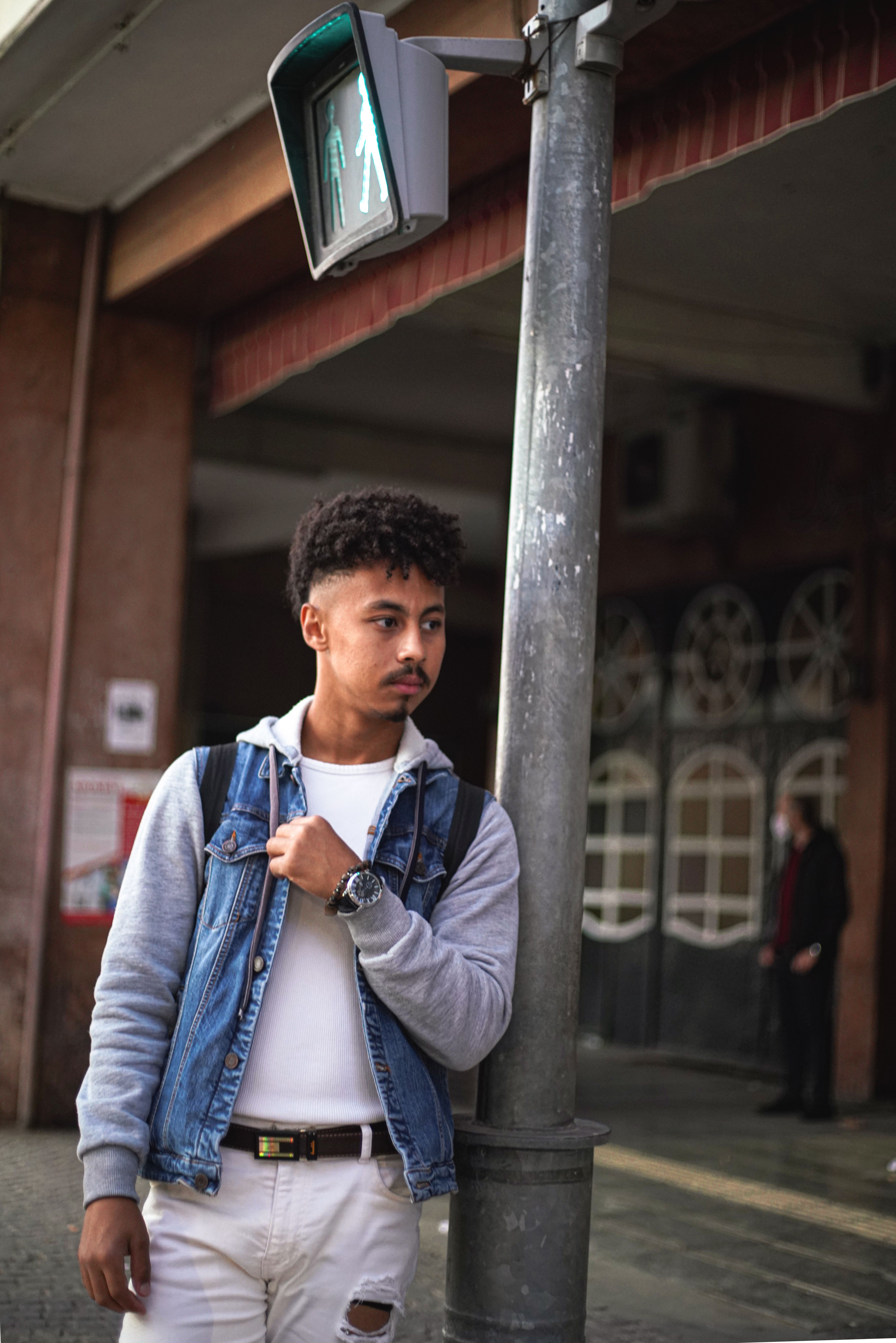 Man Wearing a Denim Jacket Leaning on a Post · Free Stock Photo