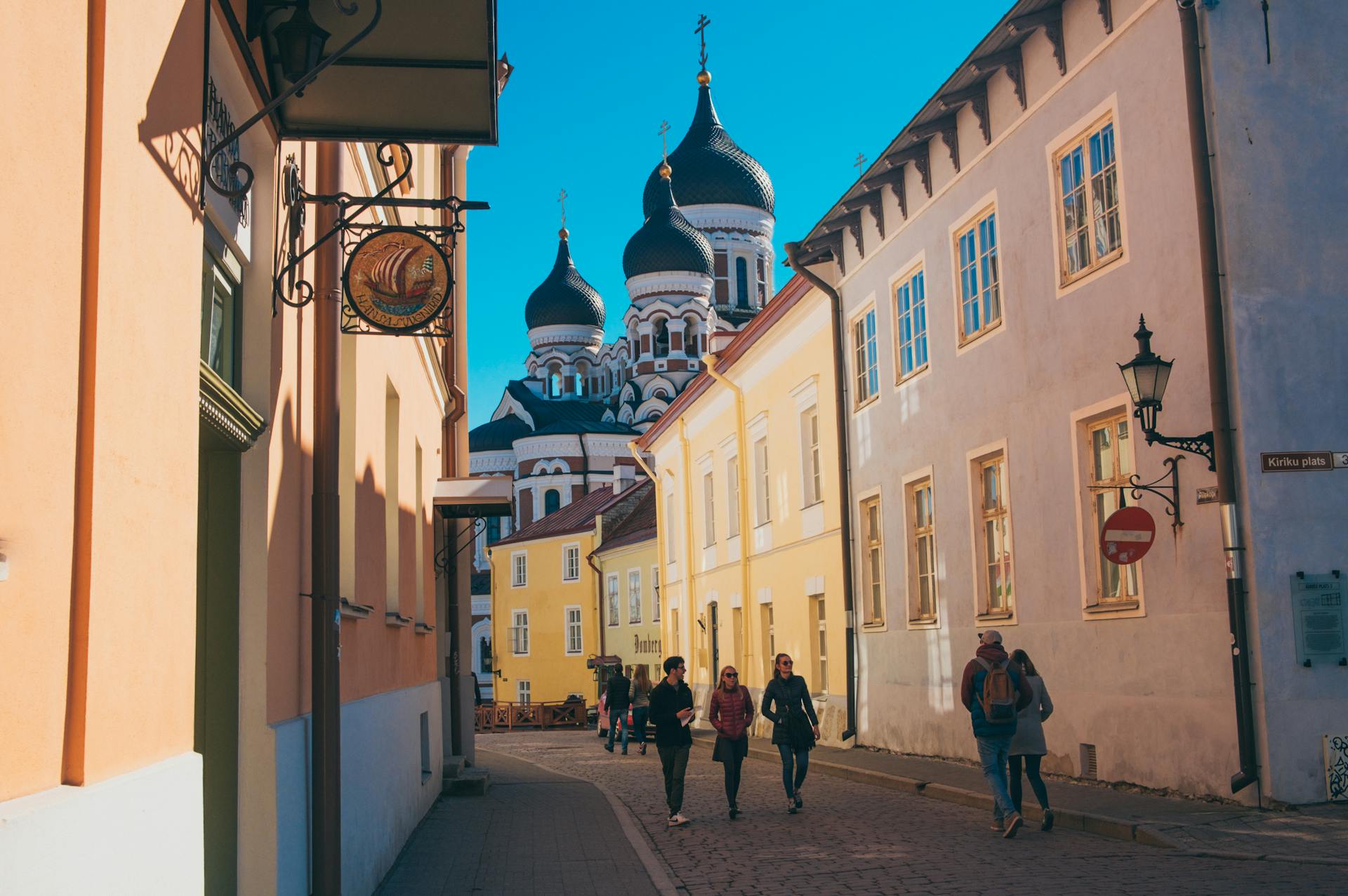 Charming street in Tallinn, Estonia with view of Alexander Nevsky Cathedral under clear blue skies.