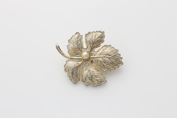 Close-Up Shot Of A Leaf Brooch On A White Surface