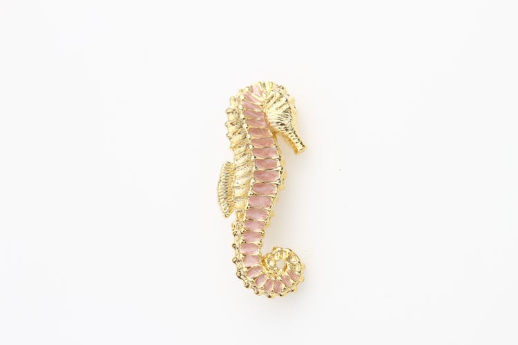 Close-Up Shot Of A Seahorse Brooch On A White Surface