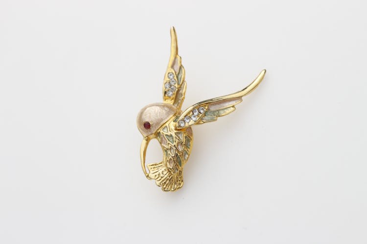 Close-Up Shot Of A Bird Brooch On A White Surface