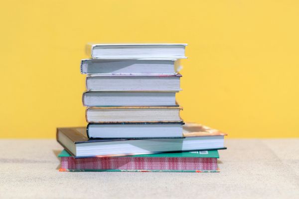 Stack of books against a bright yellow wall — photo by Gilmer Diaz Estela on Pexels