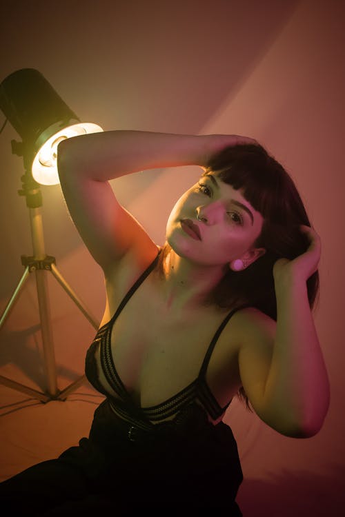 Young sensual tender woman in erotic bra looking at camera in studio with glowing projector