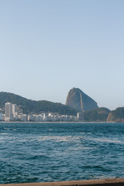 Stunning panoramic view of Sugarloaf Mountain with ocean foreground in Rio de Janeiro, under a clear blue sky.