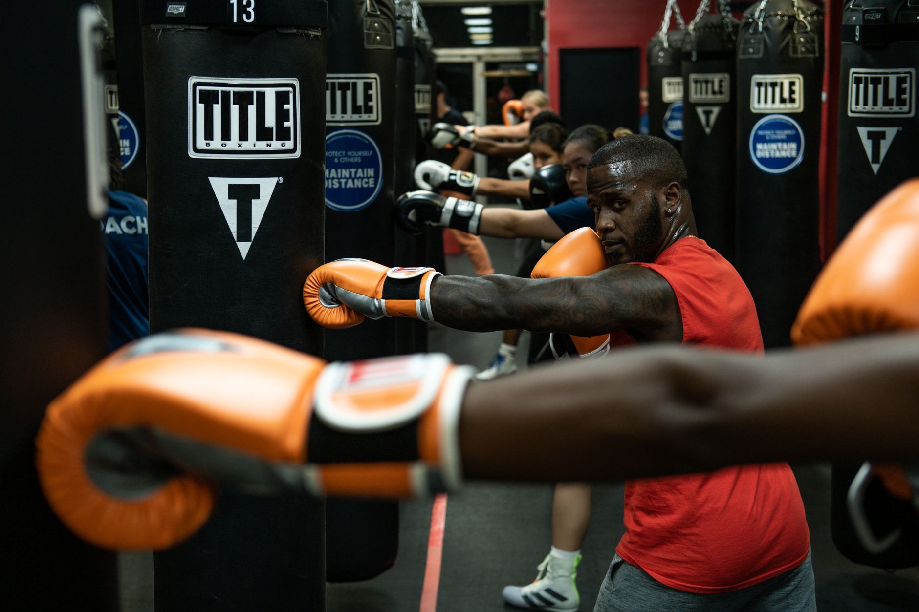Group of athletes practicing boxing with punching bags indoors.